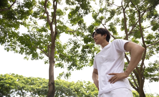 Uomo asiatico in camicia bianca felice nel parco concetto per uno stile di vita salutare nel parco