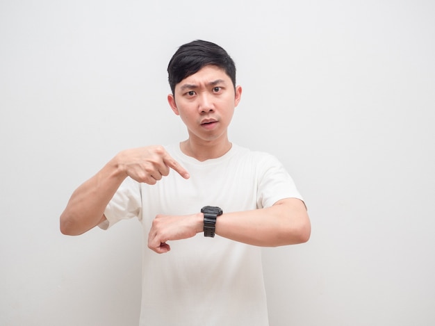 Asian man white shirt point finger at watch in hand with serious face look at camera late and busy