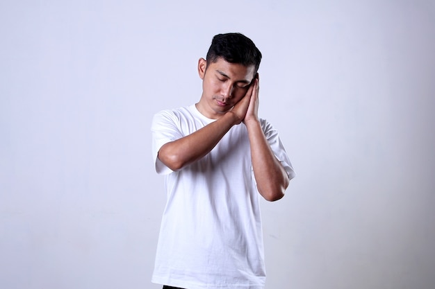 Asian man in white shirt with sleeping expression using hand on left cheek