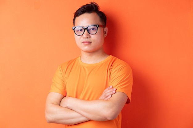 Asian man with arms crossed on orange