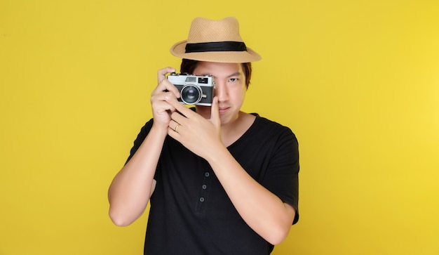 Uomo asiatico con fotocamera su sfondo giallo