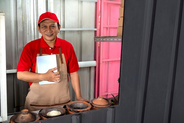 Asian man with a hat and apron holding the tablet