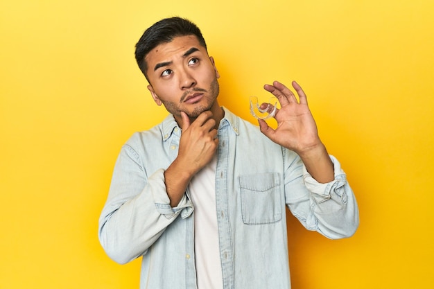 Asian man with invisible dental corrector looking sideways with doubtful and skeptical expression