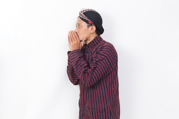 asian man with javanese traditional cloth lurik shouting and yelling announcing isolated on white