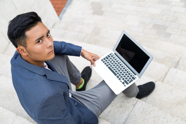 Asian man with laptop on stairs