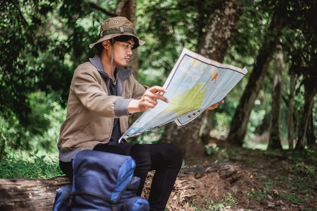 Asian man with map and hat sitting and seeing the map