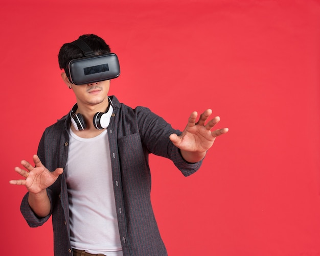 Asian man with virtual headset on red wall