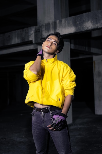An asian man with a yellow jacket and black hair posing very gallantly
