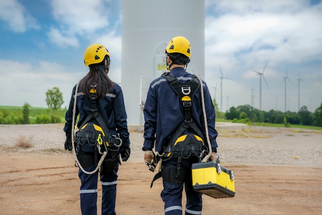 タイの風力発電所で安全な風力タービンの準備と進捗チェックを行うアジア人男性と女性の検査エンジニア。