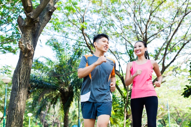 Asian man and woman jogging in city park