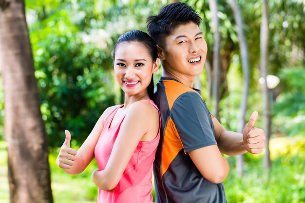 Asian man and woman take a break after fitness jogging in city park