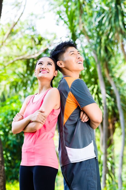 Asian man and woman take a break after fitness jogging in city park