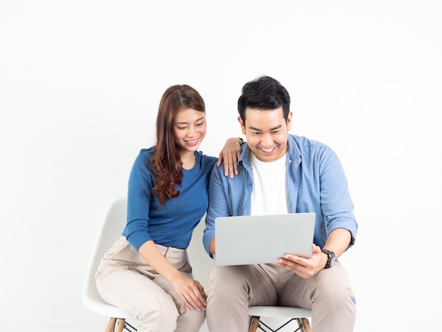 Uomo e donna asiatici che parlano con il computer portatile per l'affare su fondo bianco