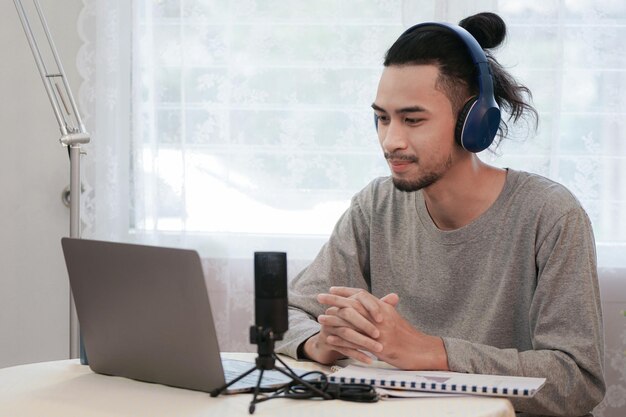 Foto l'uomo asiatico lavora da casa. il giovane sta usando il laptop per la riunione della teleconferenza. piattaforma online di business della tecnologia della comunicazione. business concept passaggio al lavoro a distanza.