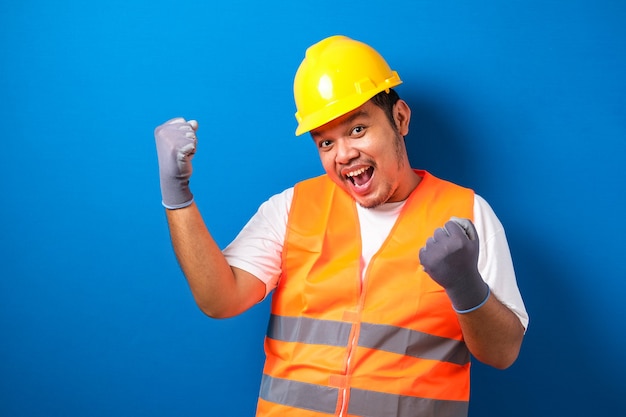 Asian man worker wearing safety helmet lookis happy celebrating his victory by clenching his fists 