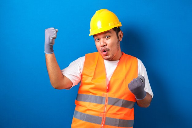 Asian man worker wearing safety helmet lookis happy celebrating his victory by clenching his fists 