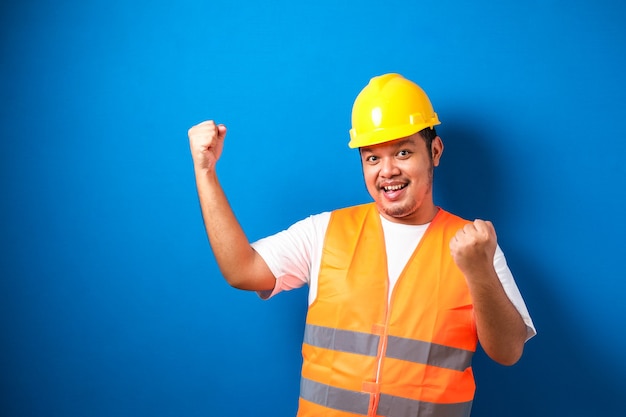 Asian man worker wearing safety helmet lookis happy celebrating his victory by clenching his fists 