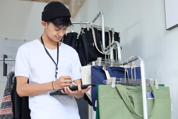 ストックをチェックするためにデジタルタブレットを持った小売店の店員として働くアジア人男性