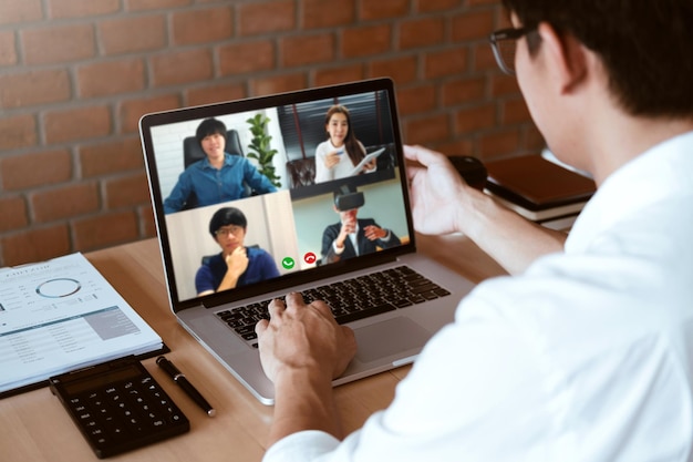 Foto uomo asiatico che lavora da casa utilizza smart working e videoconferenza online incontro con team asiatico utilizzando laptop e tablet online in videochiamata per nuovi progetti