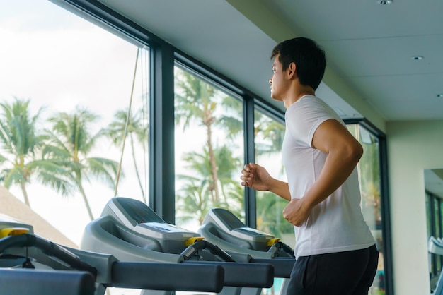 Uomo asiatico che lavora su un tapis roulant in un centro fitness del resort al mattino.