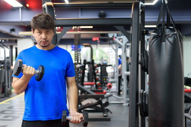 Asian man working out with dumbbells in the gym