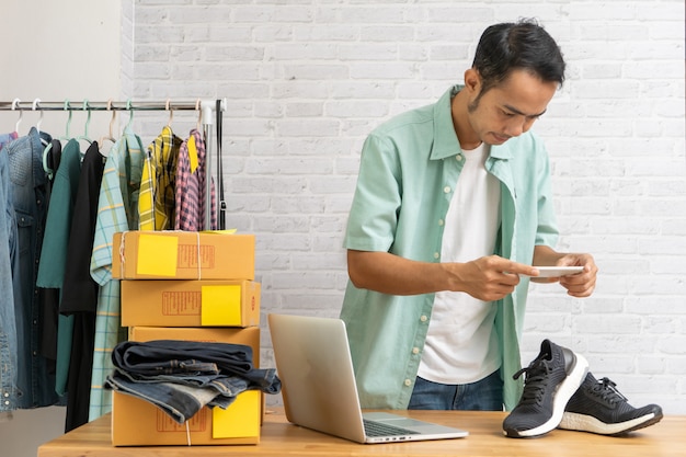 Asian man working taking photo to shoes with smart phone