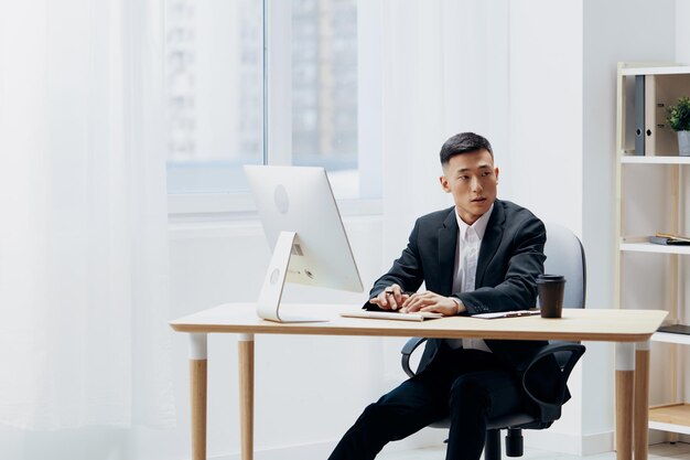 Asian man works at the computer glass of coffee emotion office\
workspace