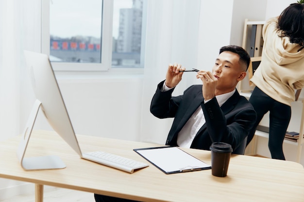 Asian man works at the computer glass of coffee emotion office\
workspace