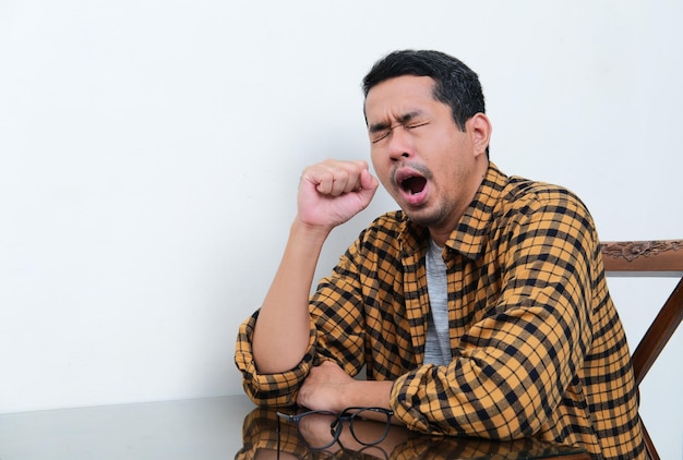 Asian man yawning when sitting alone