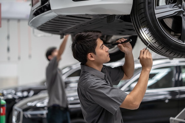 Asian mechanic Checking and torch tire in maintainance service center which is a part of showroom