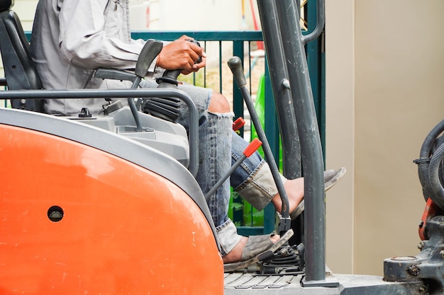 Asian mechanic using excavator in a small place