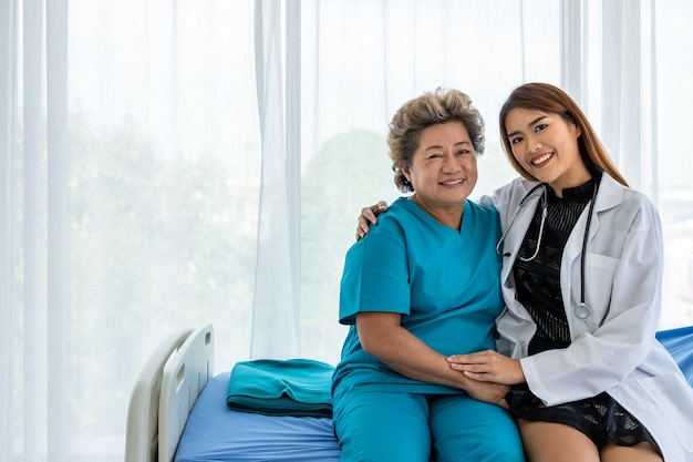 Asian medical doctor motivate senior elderly woman female patient hand sitting on bed looking at camera