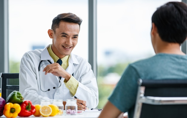 Asian medical practitioner give information and advice and explaining prescription to man patient during work in hospital