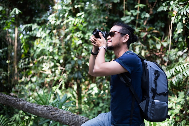 Asian men backpacks and traveler walking together and happy are taking photo on forest, Relax time on holiday concept travel