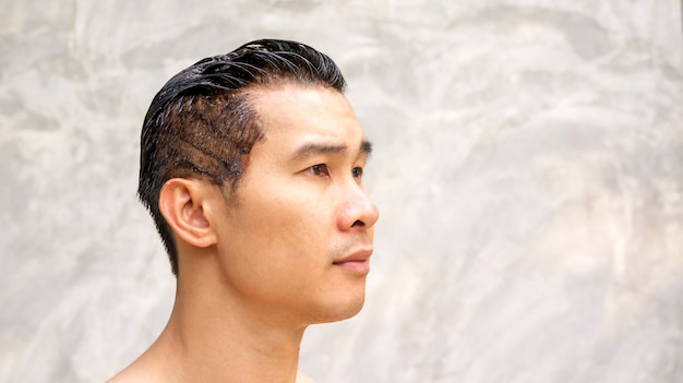 Asian men dye his hair color on a gray background.