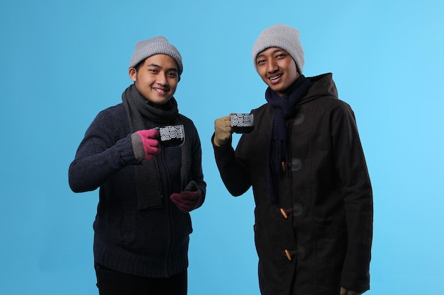 Asian men wrapped in winter clothes with cup in hands