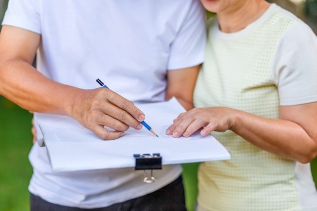 Asian middle-aged couple talking and designing garden plan together in backyard.