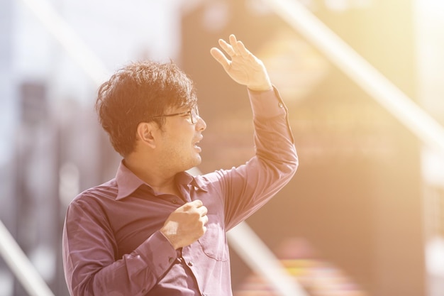 Photo asian middle-aged man feels hot stands outdoor in sunny day