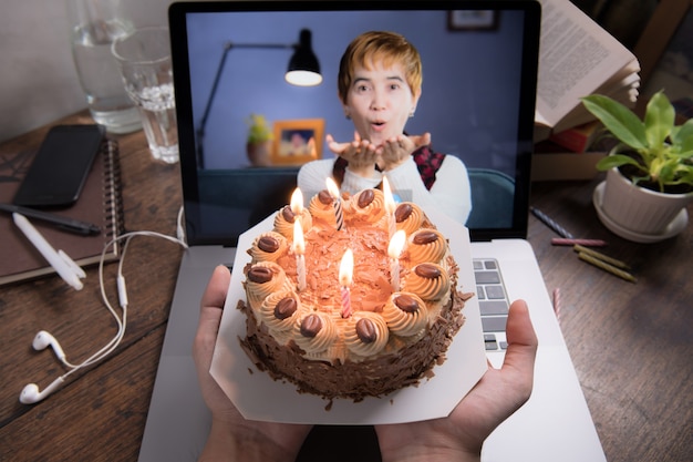 Asian middle aged woman feeling happy while celebrating virtual birthday via video call