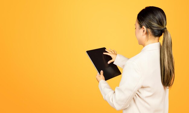 Asian millennial woman in suit touching tablet with empty screen back