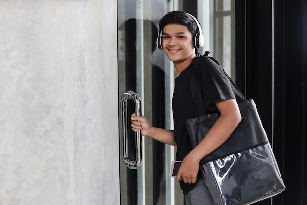 Asian Millennial young maln open glass doors while smiling to the camera