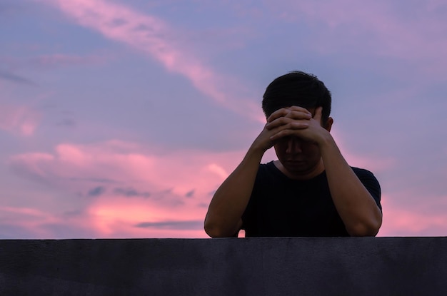 Asiatico miserabile uomo depresso stare da solo con sfondo cielo depressione e concetto di salute mentale