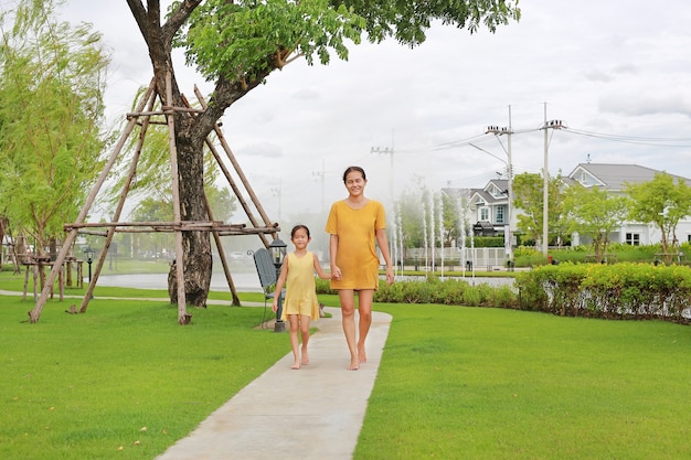 Asian mom and daughter hand in hand walking in garden