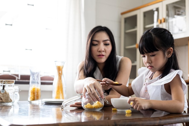 Asian mom and daughter have fun cooking in the kitchen at home.