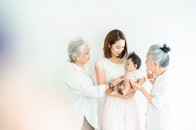 Asian mom holding a baby and two senior women