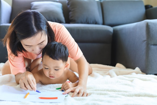 Asian mom teaching her baby boy draw