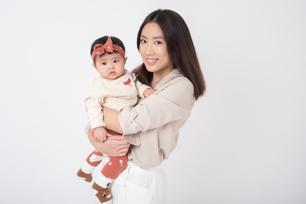 Asian mother and adorable baby girl are happy on white wall