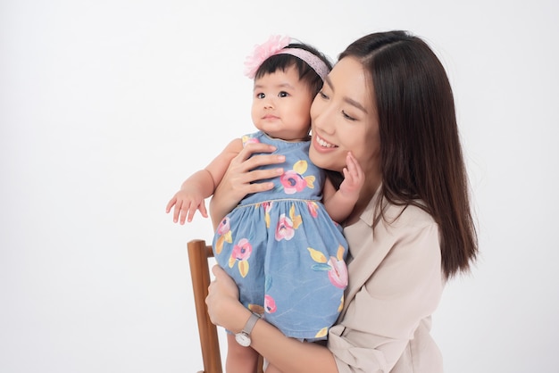 Asian mother and adorable baby girl are happy on white wall