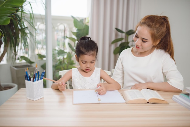 Asian mother and daughter doing home work together in living room