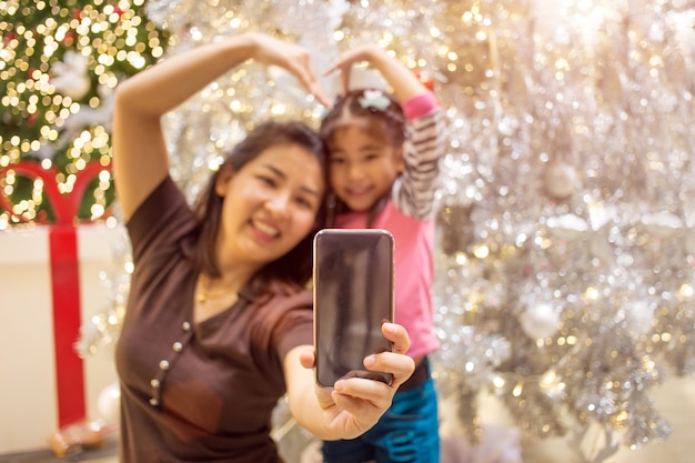 Photo asian mother hand hold mobile with daughter to take selfie photo